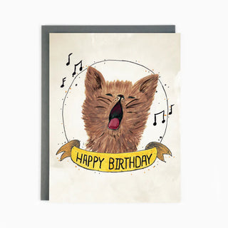 A white card with a brown singing cat and musical notes surrounding it and the words 