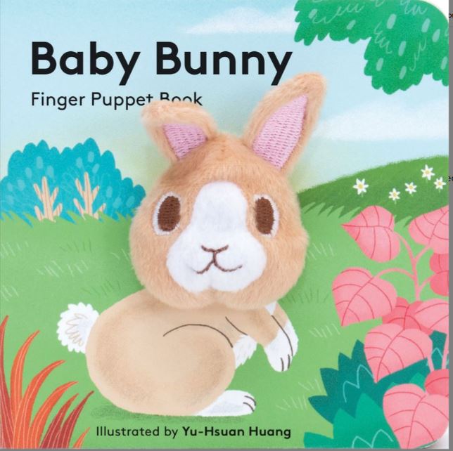 A book with a bunny sitting in a meadow. The head of the bunny is a finger puppet