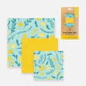 3 different sized beeswax wraps, one with yellow flowers and leaves on a teal background, one with bees and dashed lines on a yellow background, and another with the same pattern as the first but in a smaller size