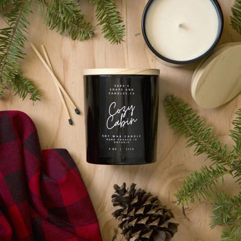 Cozy Cabin - 9oz Soy Candle - Black glass 9oz soy candle labeled Cozy Cabin with wooden matches, pinecone, and red plaid fabric, handmade Canadian gift.
