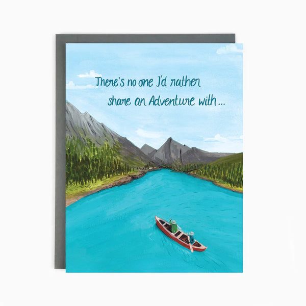 A scenic card with mountains and water and people in a canoe in the water and the words 