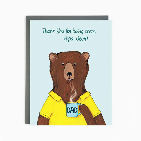 A blue card with a brown bear wearing a yellow polo holding a mug and the words 