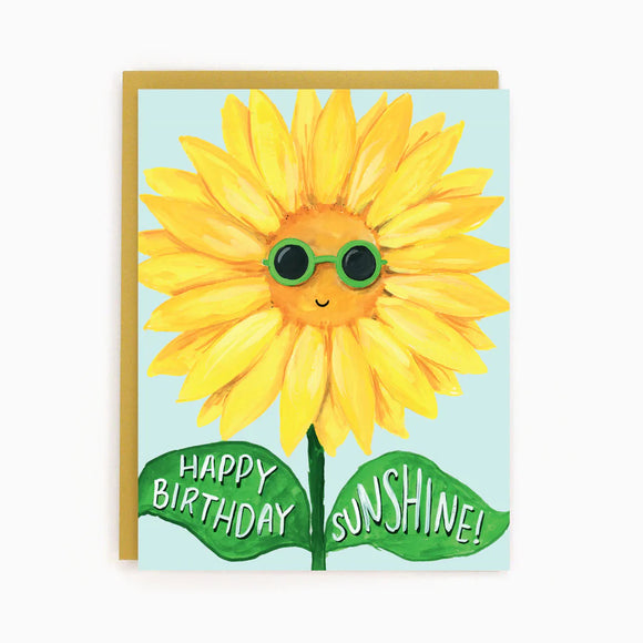 A light blue card with a picture of a sunflower wearing sunglasses and the words "Happy Birthday Sunshine!"