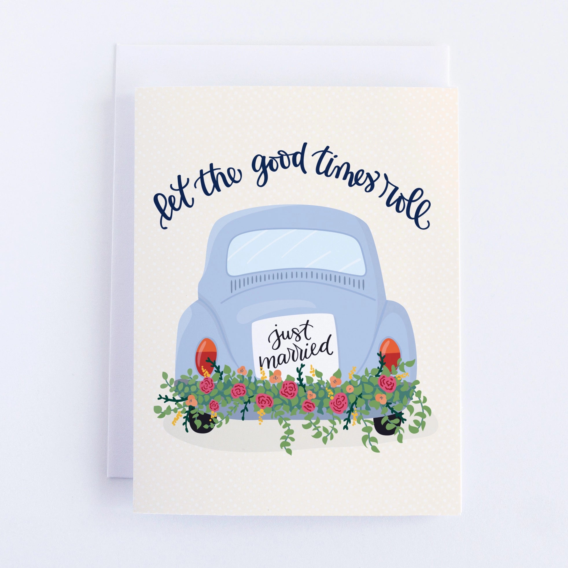 A white card with a car with a 'Just Married' sign on their bumper alongside some flowers, and the words "Let the good times roll"