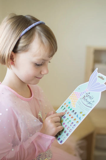Mermaid Sticker Earrings - Colorful mermaid sticker earrings sheet held by child wearing pink dress and blue headband, unique handmade Canadian gift.