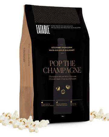 Pop the Champagne - Gourmet Popcorn (Eatable) - Black and brown bag of Pop the Champagne gourmet popcorn with gold lettering, surrounded by popcorn, unique Canadian.