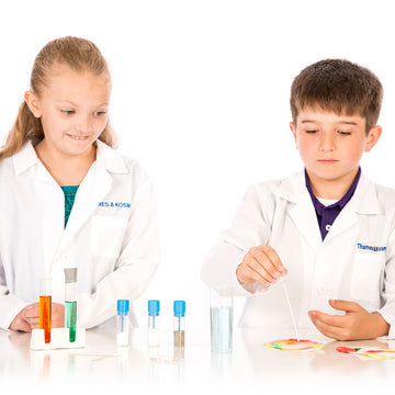 2 kids wearing lab coats playing with the Kids First Chemistry Set