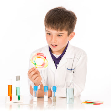A kid in a lab coat playing with the Kids First Chemistry Set