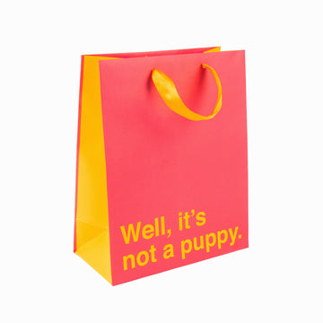 Funny Gift Bag: Not a Puppy: Pink w/ Light Orange - Pink and light orange gift bag with yellow handles and "Well, it's not a puppy." text, unique handmade Canadian design.