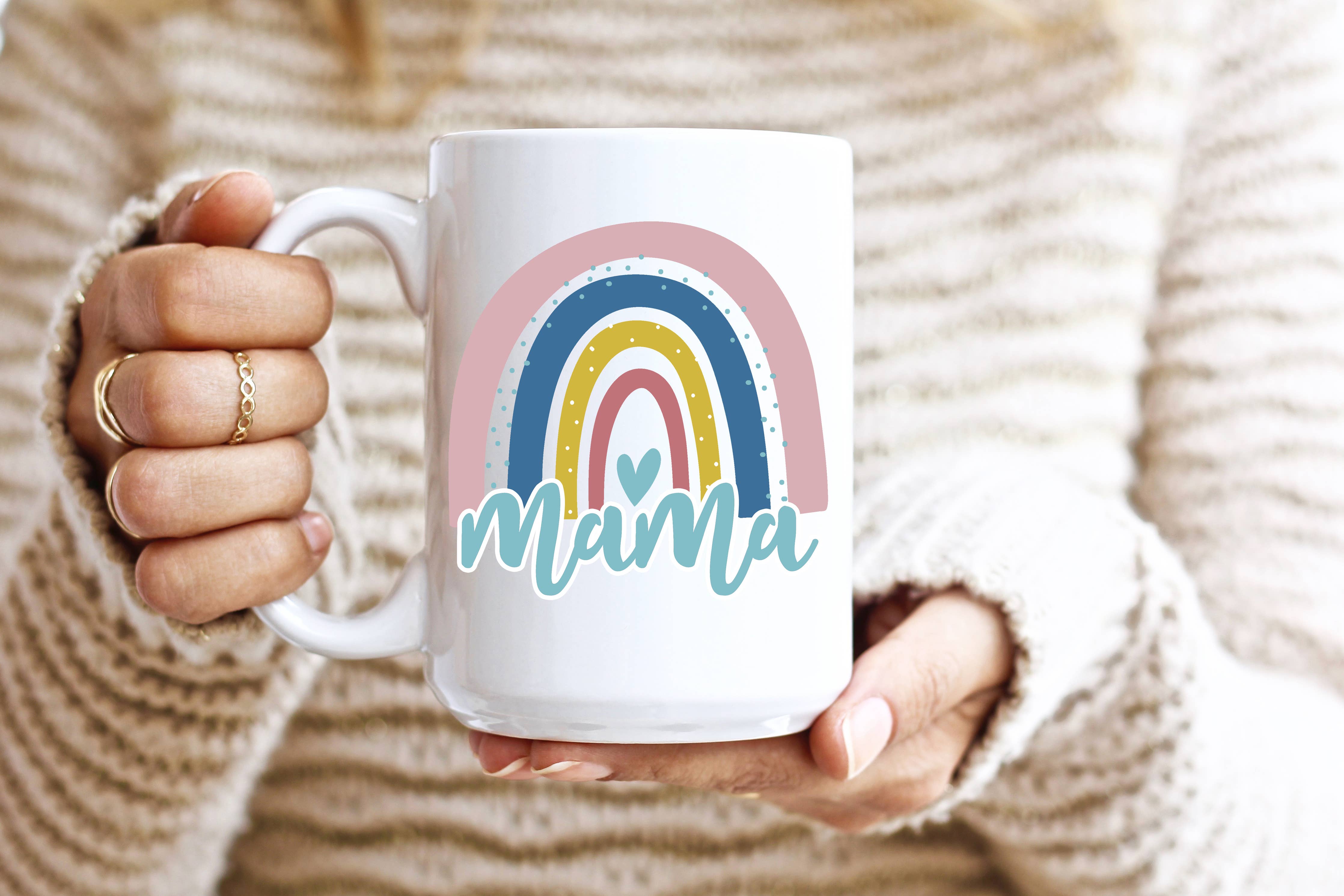 A white mug with a rainbow and the words "Mama" on it