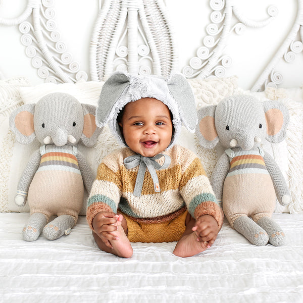 2 elephant stuffies on either side of a baby