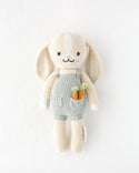 A bunny stuffy wearing blue overalls with carrots in its pocket