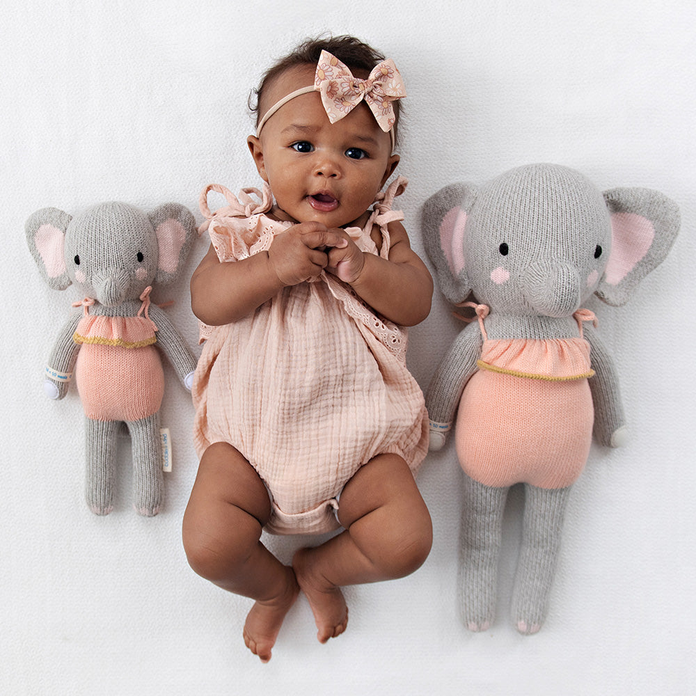 2 different sized elephant stuffies on either side of a baby