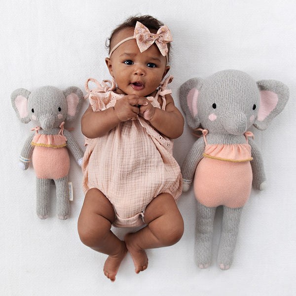 2 different sized elephant stuffies on either side of a baby