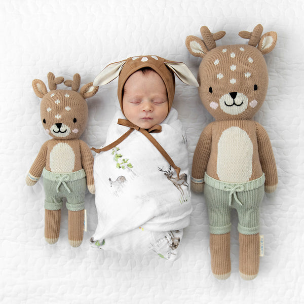 2 different sized stuffies on either side of a baby
