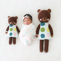 2 different sized brown bear stuffies on either side of a sleeping baby