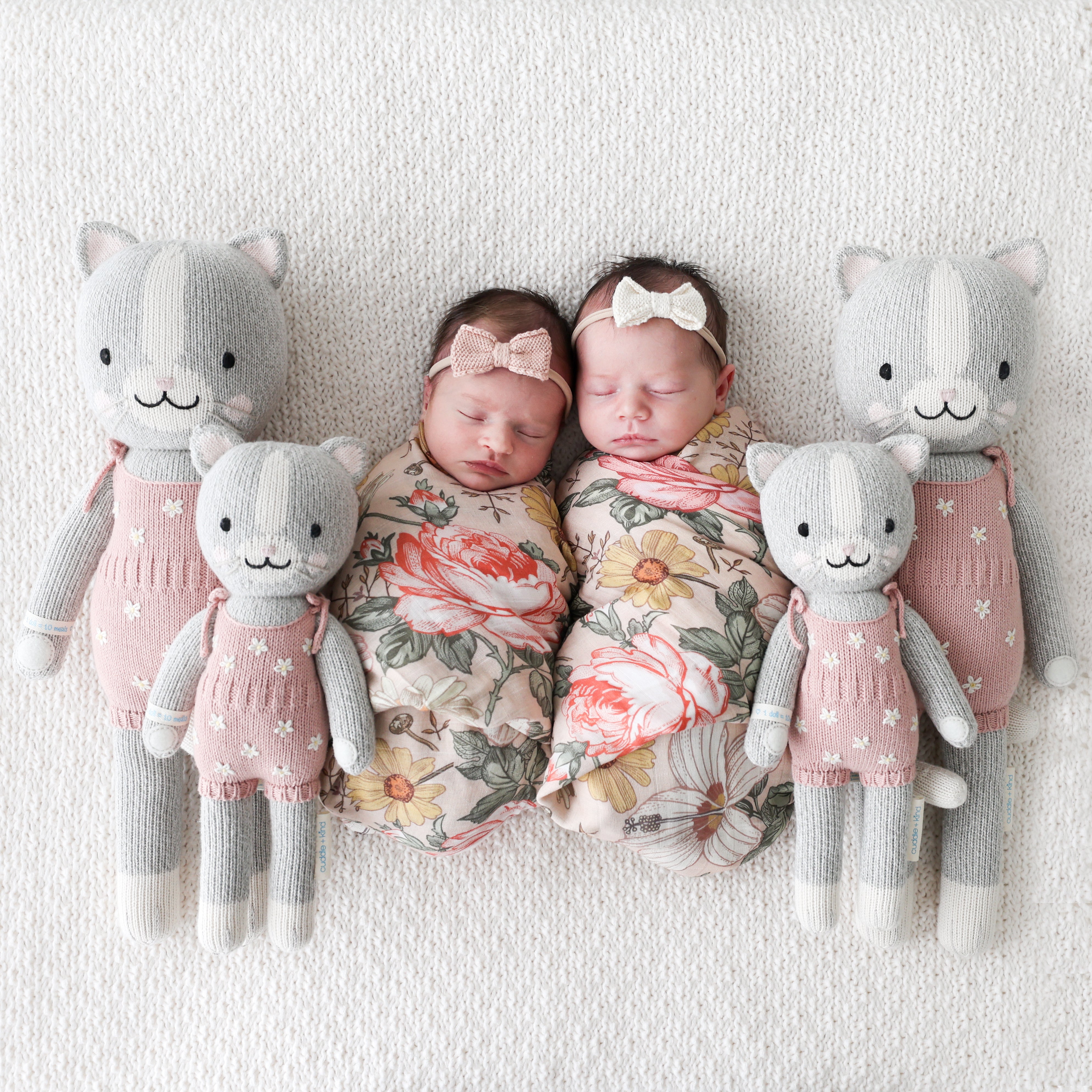 4 cat stuffies on either side of 2 babies sleeping 