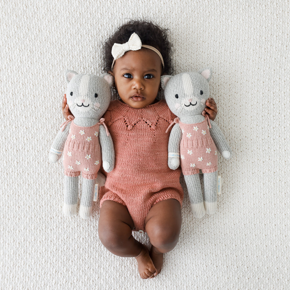 2 cat stuffies on either side of a baby