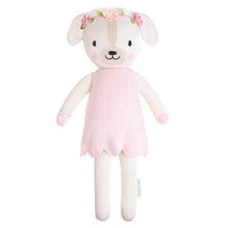 A dog plushie wearing a pink dress and a flower crown 